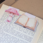 Комплект от два розови магнитни книгоразделителя върху отворена книга